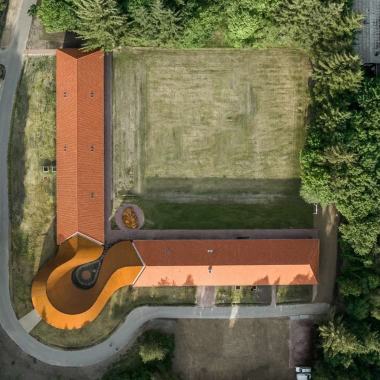 Der Blick von oben zeigt den runden Neubau, der die beiden historischen Gebäude mit den Ziegeldächern miteinander verbindet (© R_Hjortshoj) Der Blick von oben zeigt den runden Neubau, der die beiden historischen Gebäude mit den Ziegeldächern miteinander verbindet (© R_Hjortshoj)